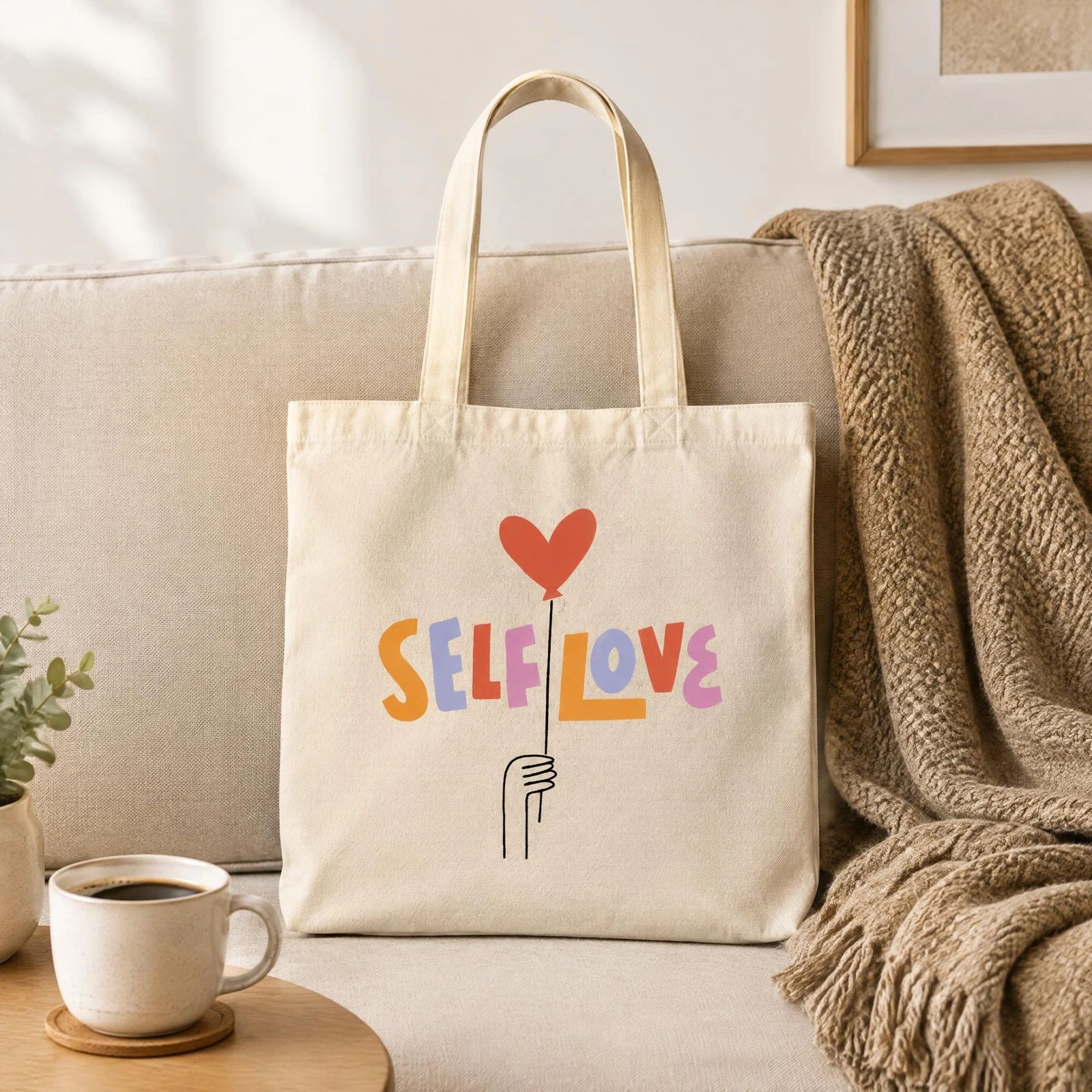 Printed canvas tote bag arranged on a sofa with a mug and neutral cushions