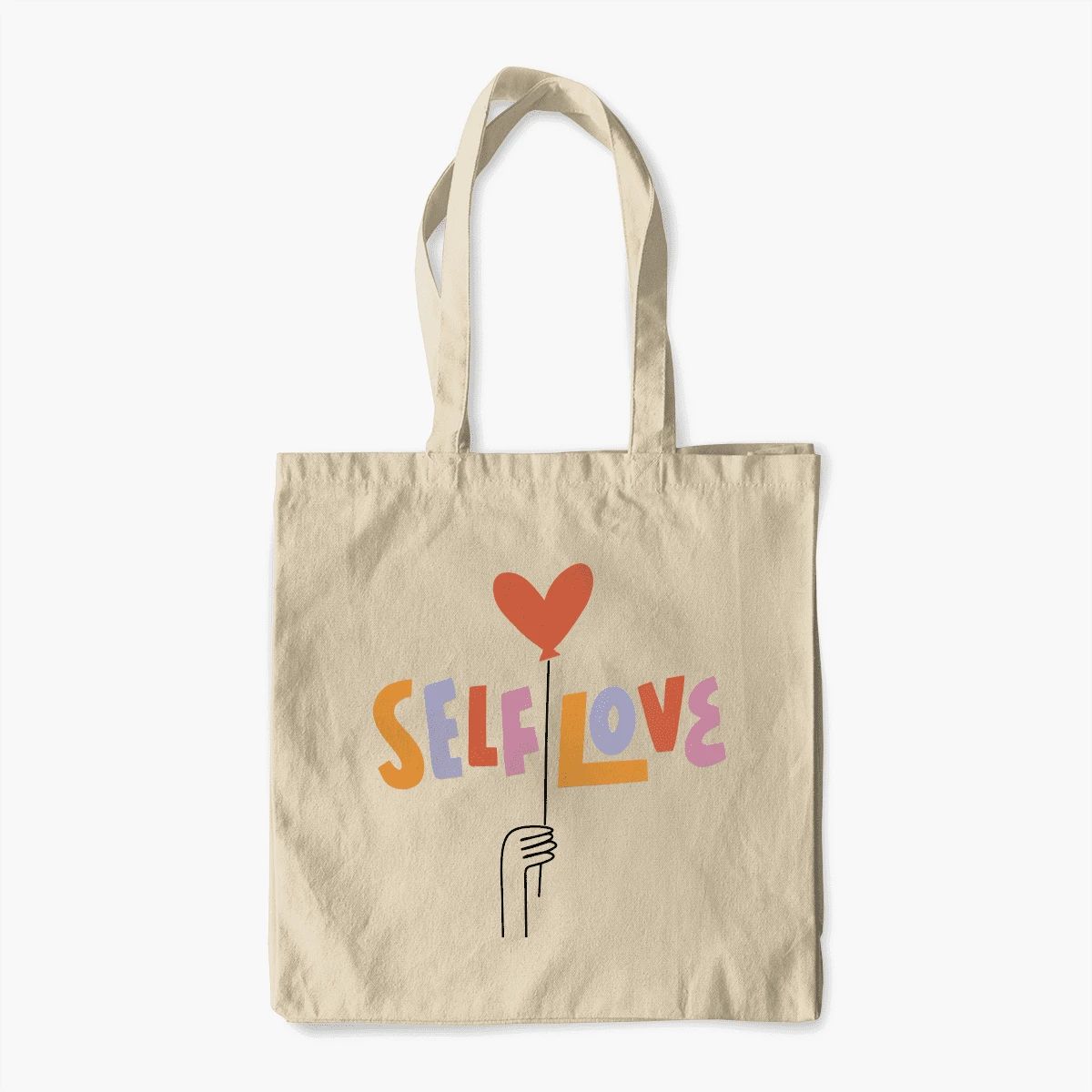 Canvas tote bag with colorful lettering beside a cup on a light surface
