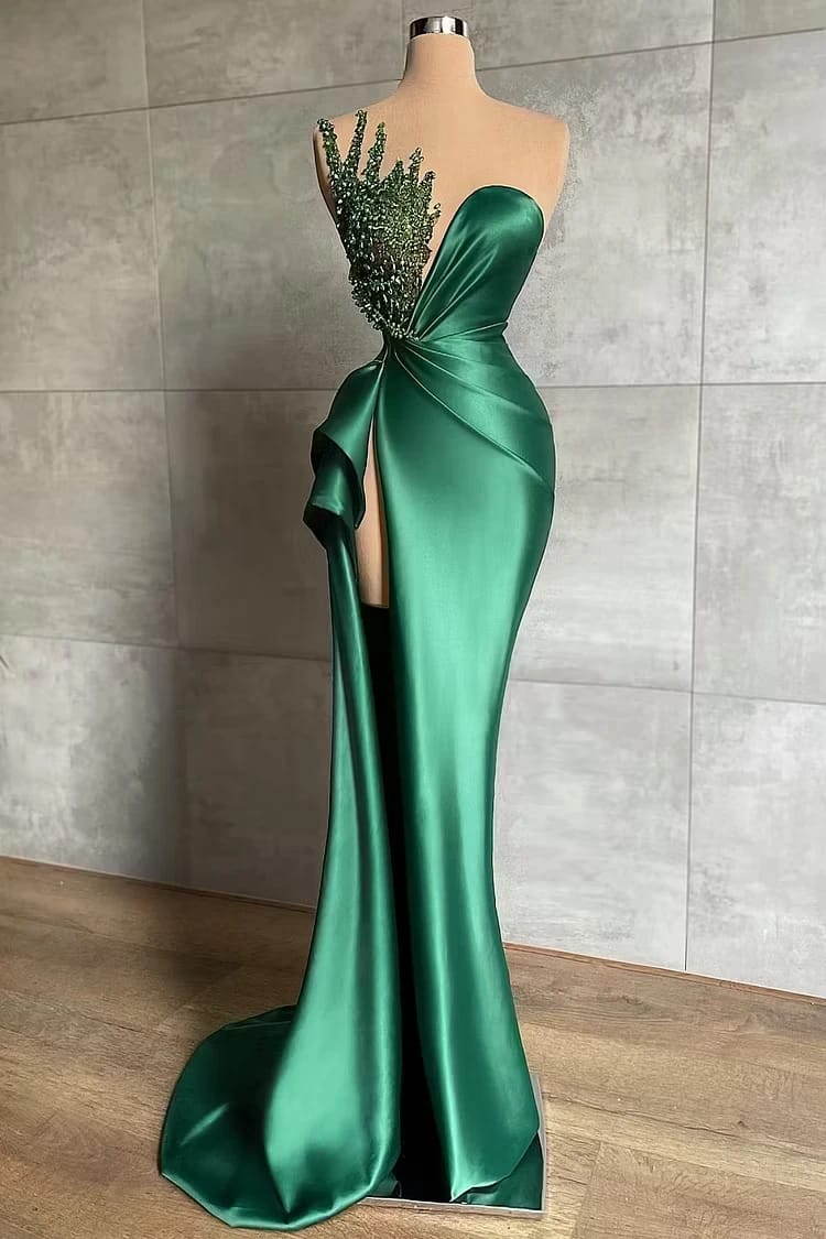 Emerald satin evening gown displayed on a dress form in front of a stone wall
