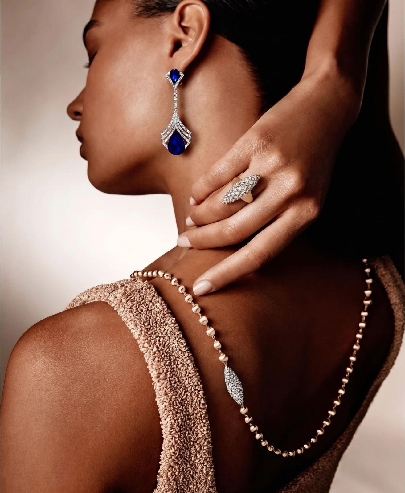 Model wearing blue gemstone drop earrings in a close-up portrait