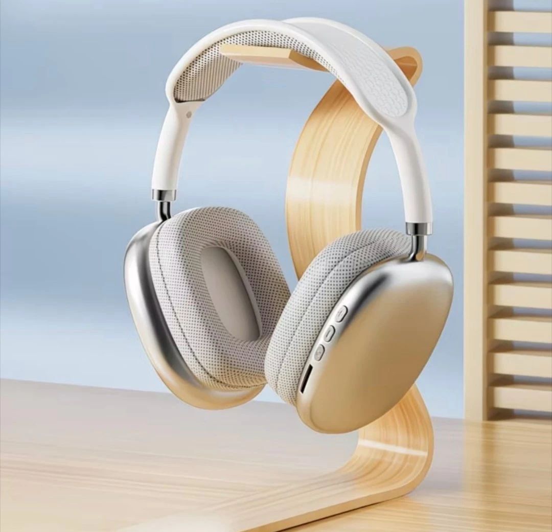 White over-ear headphones displayed on a light wood stand