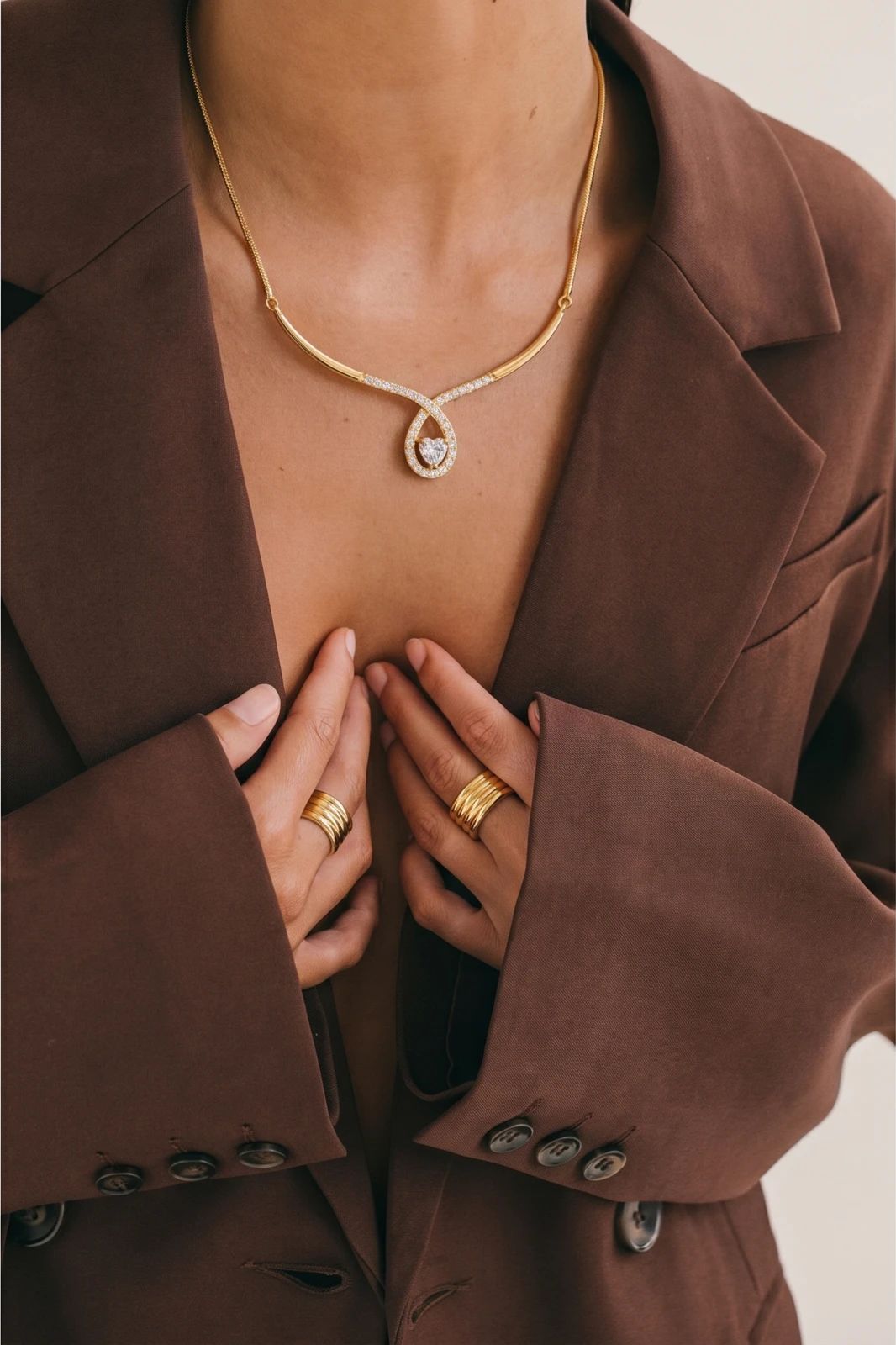 Model wearing a fine gold heart necklace above a light neckline