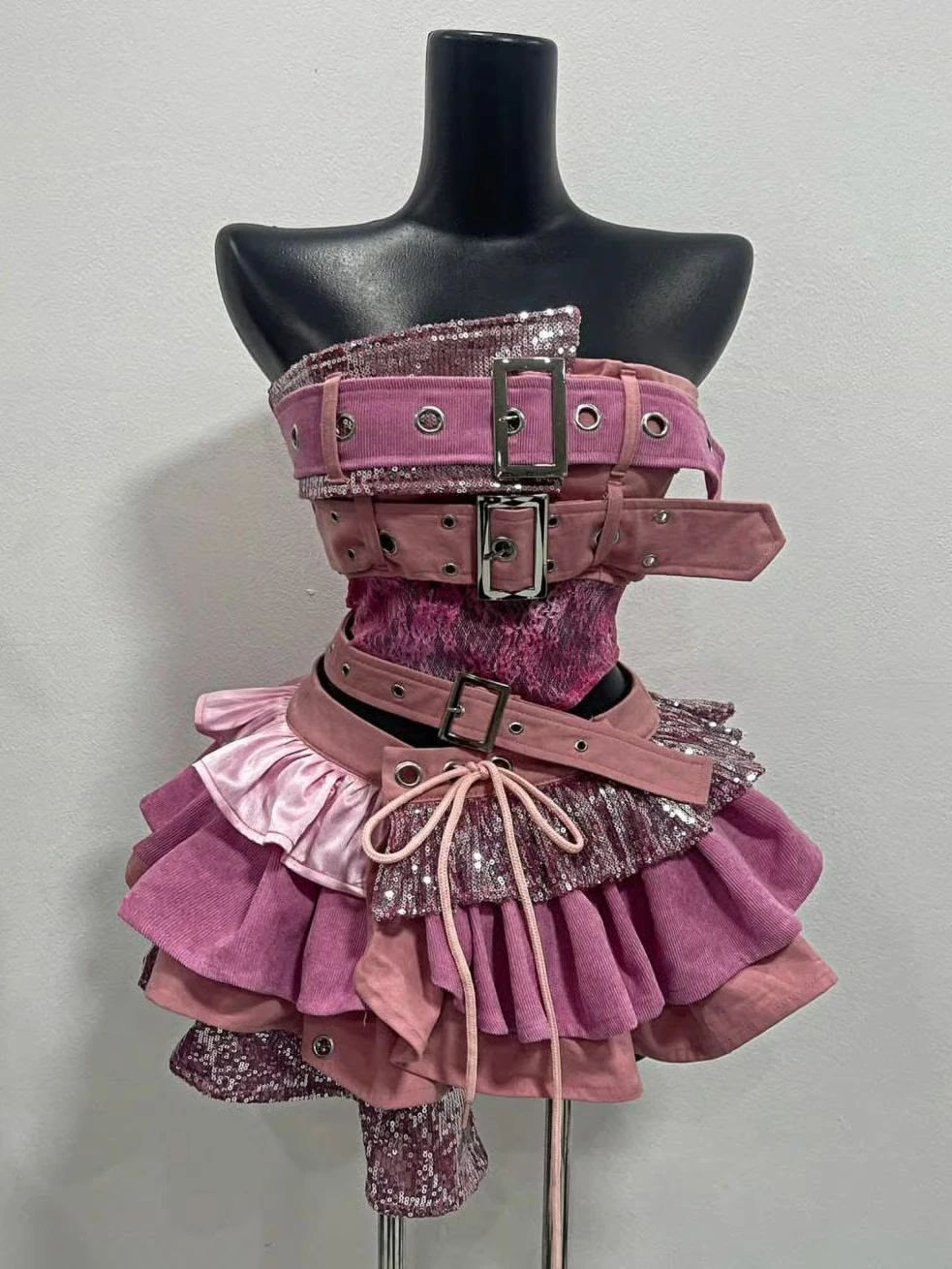 Pink layered outfit with belts and chunky black boots displayed on a mannequin