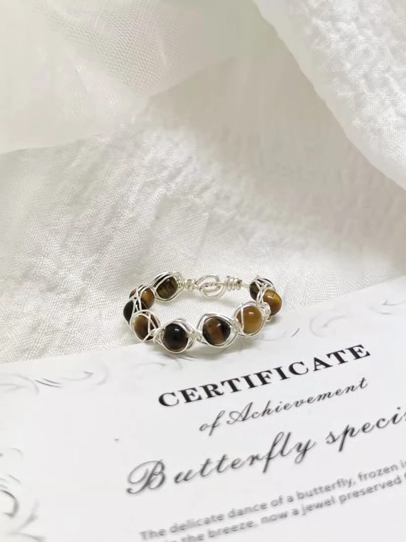 Gold ring with oval brown gemstones displayed on a printed certificate