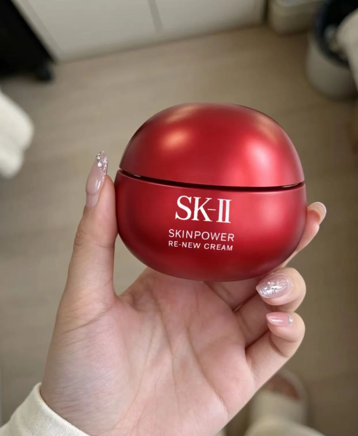 Red skincare cream jar held in a hand