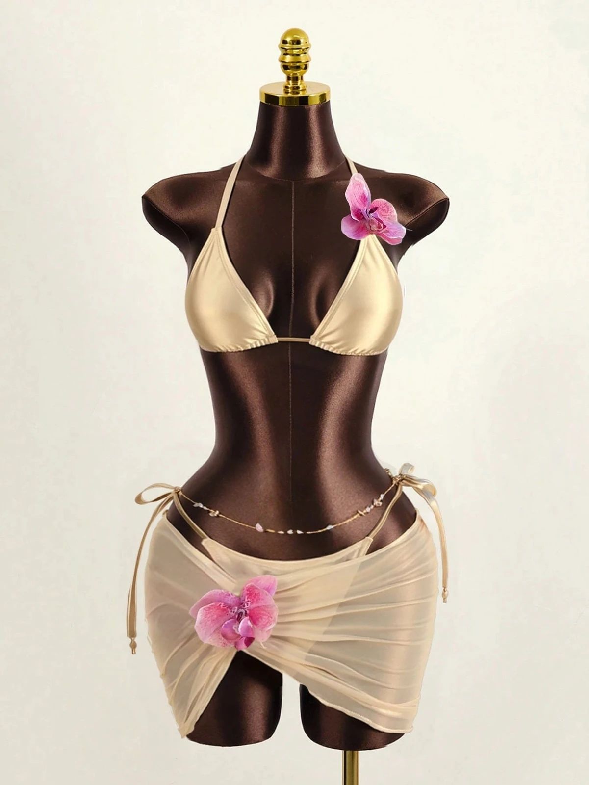 Two-piece beige swimsuit with flower detail displayed on a dark mannequin