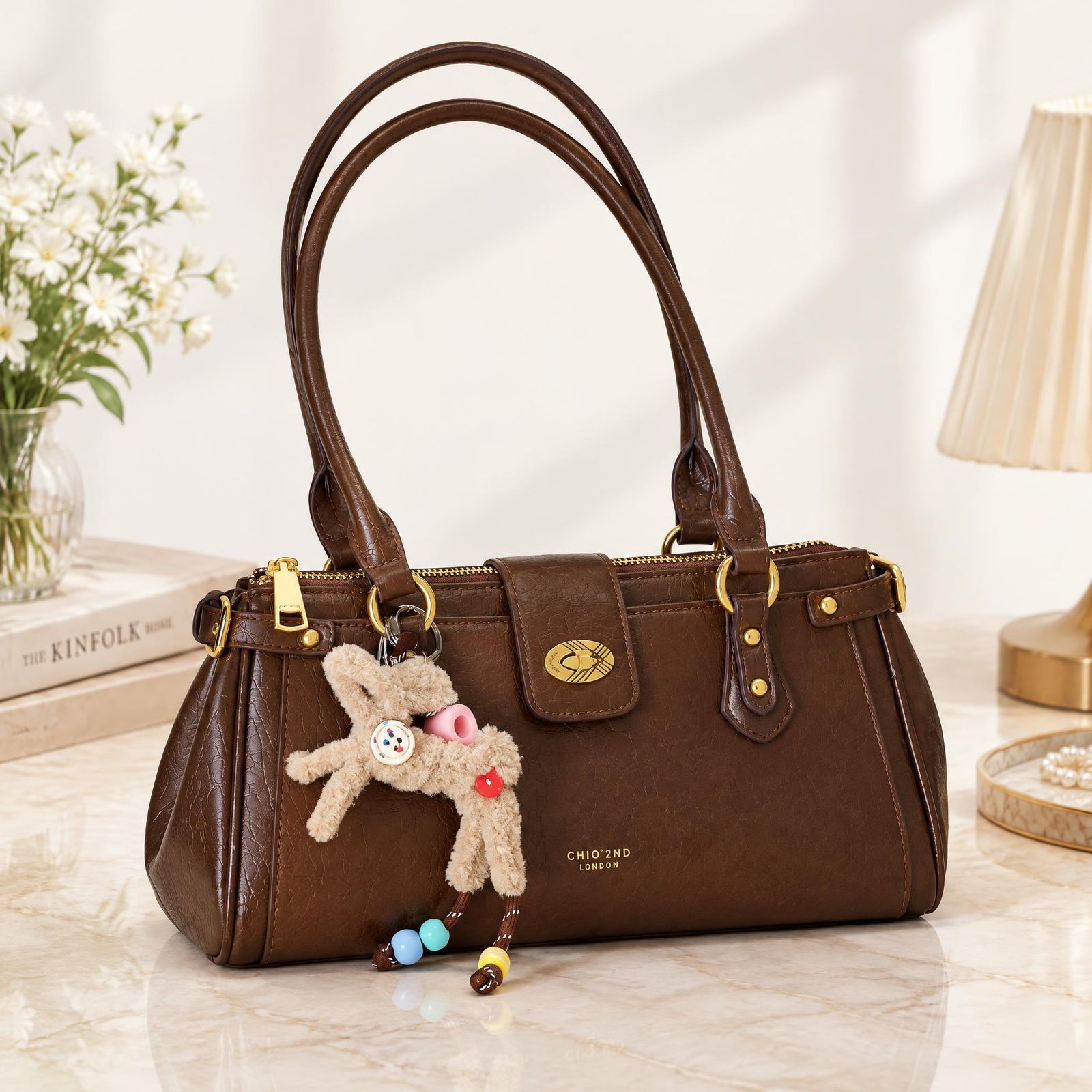 Brown leather handbag with a teddy-bear charm in a warm interior scene