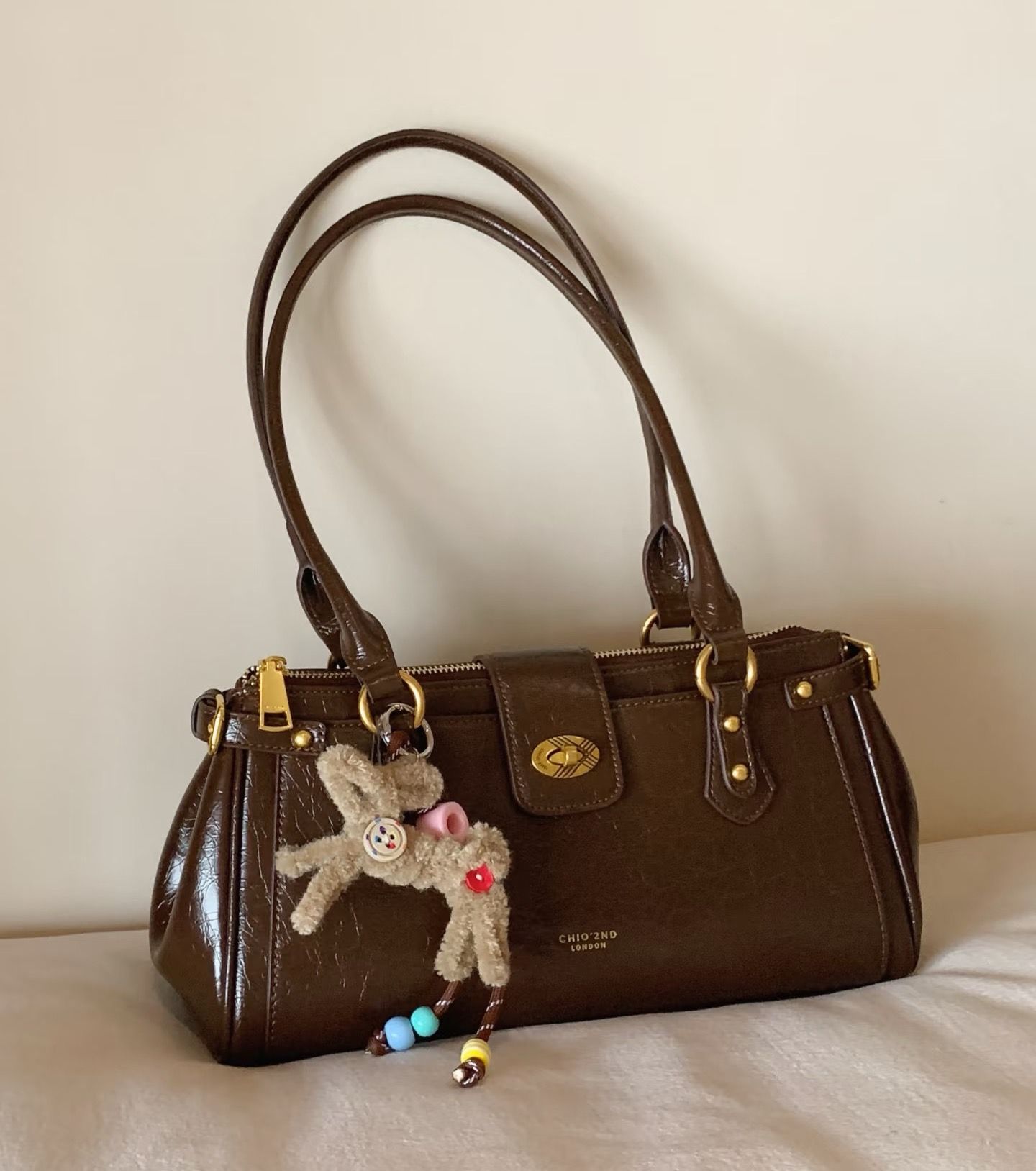 Original photo of a brown leather handbag with a teddy-bear charm