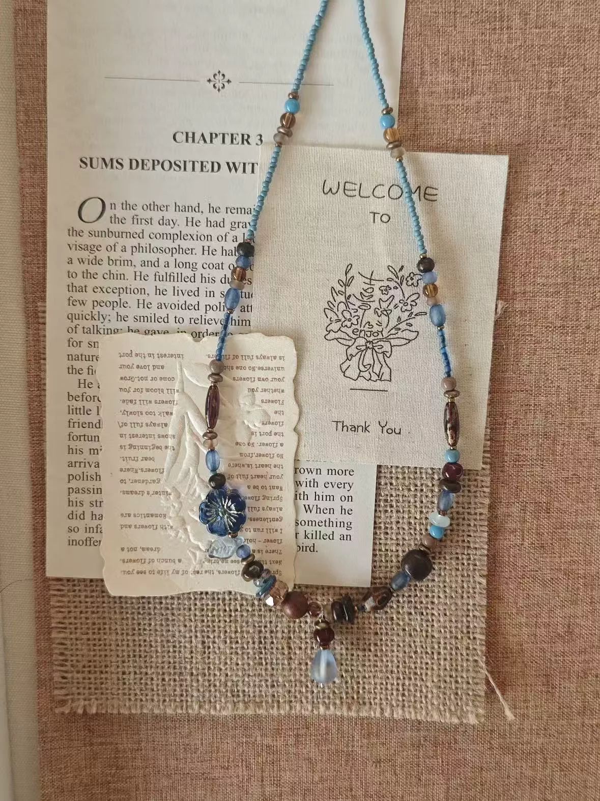 Source photo detail of a one-of-a-kind beaded necklace — pressed-glass flower bead with silver starburst center and unique neighboring beads