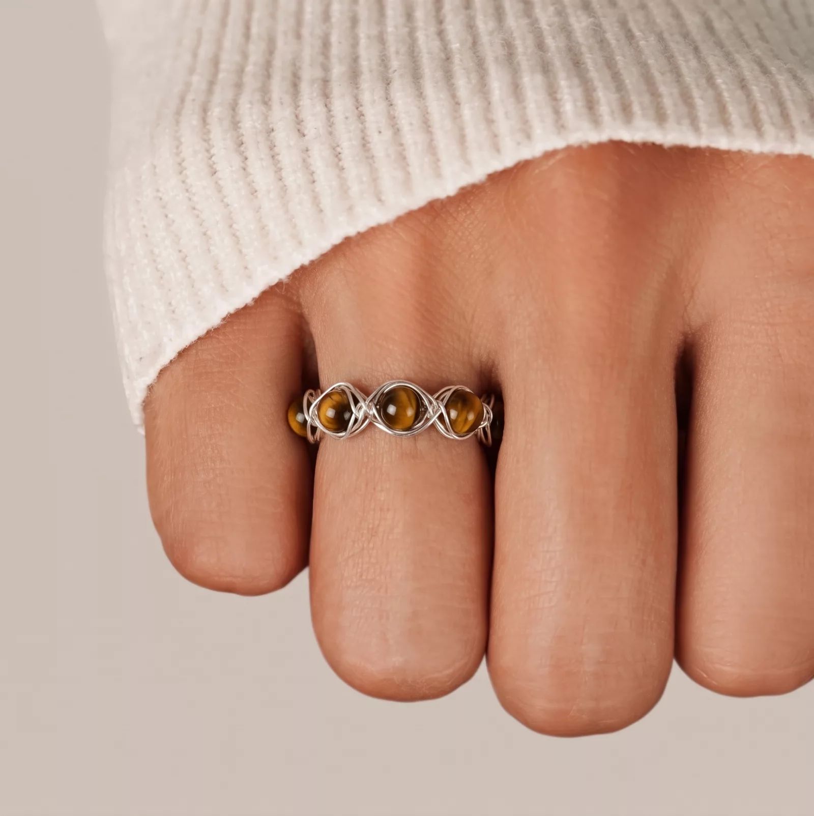 Snappyit Jewelry Model output — tiger's eye wire-wrapped ring worn on a model's finger at correct scale with natural skin tone and lighting