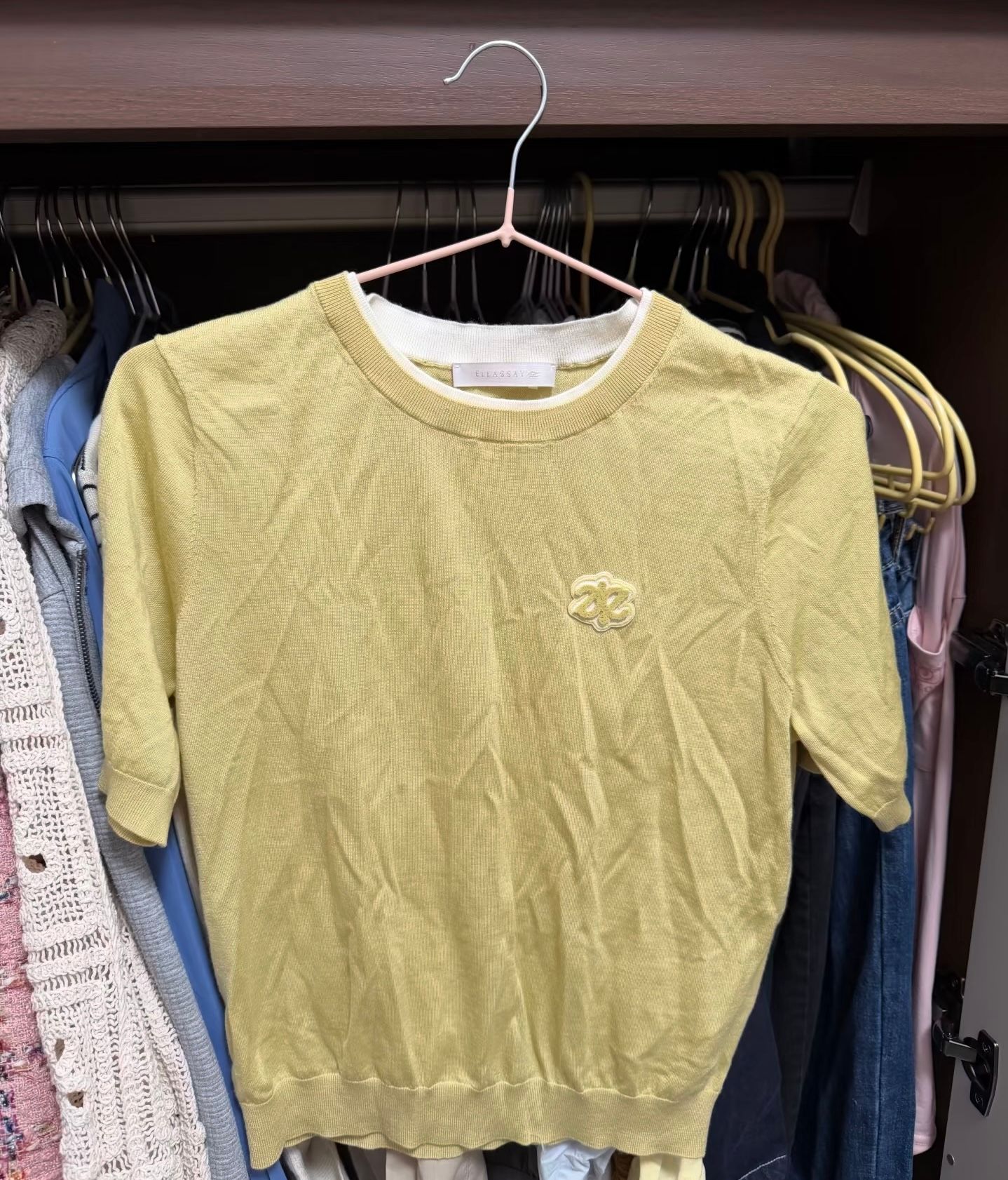 Original yellow knit top with a chest motif before wrinkle removal
