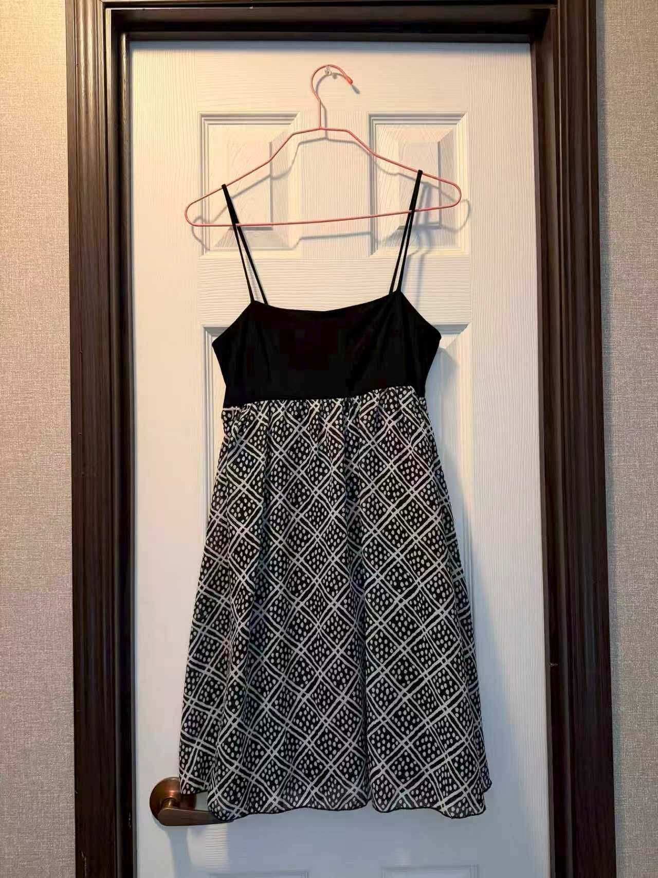 Full-length hanger photo of a black and white patterned dress with visible straps and hem