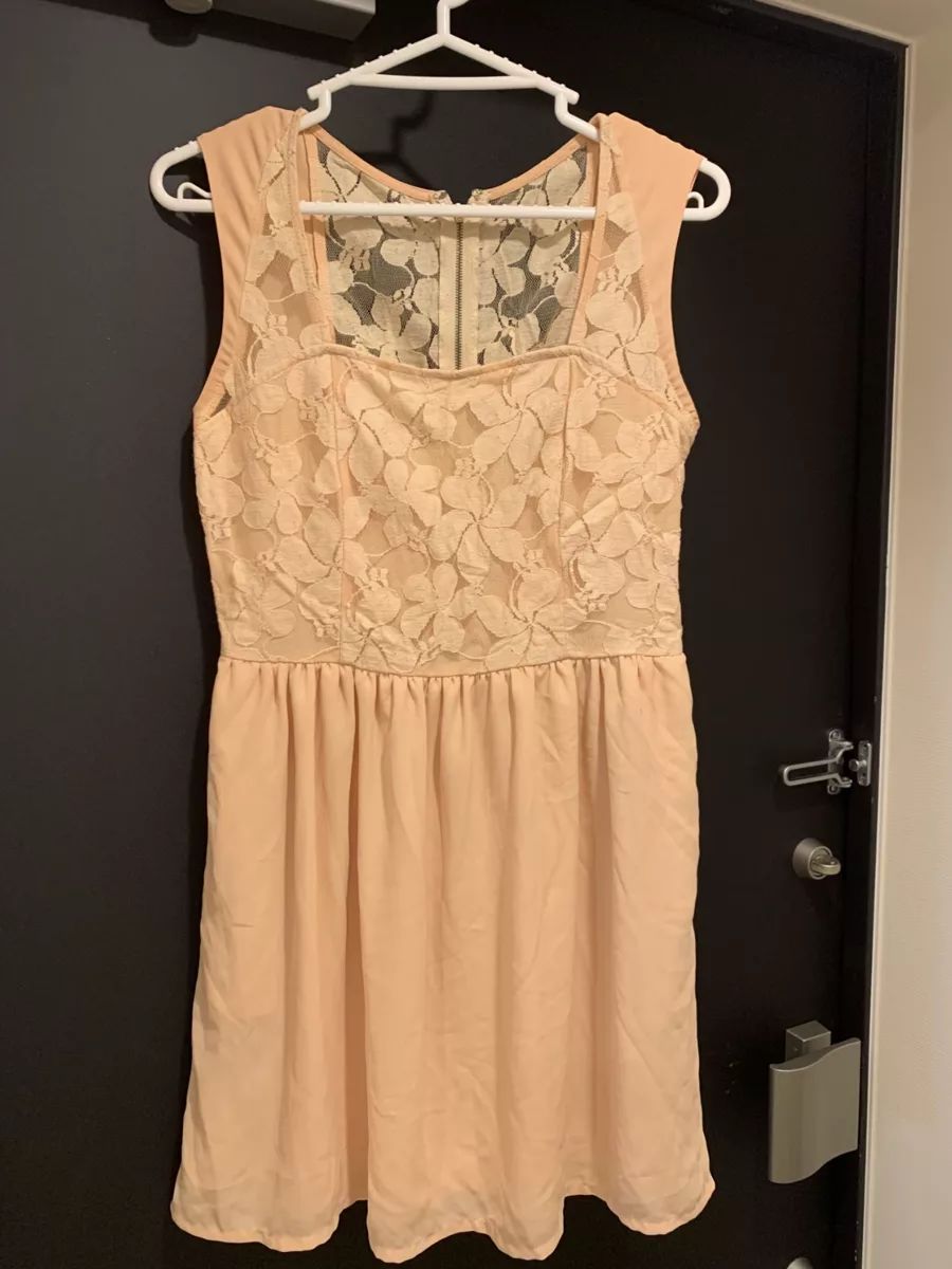 Peach lace dress hanging on a door before AI flat lay generation