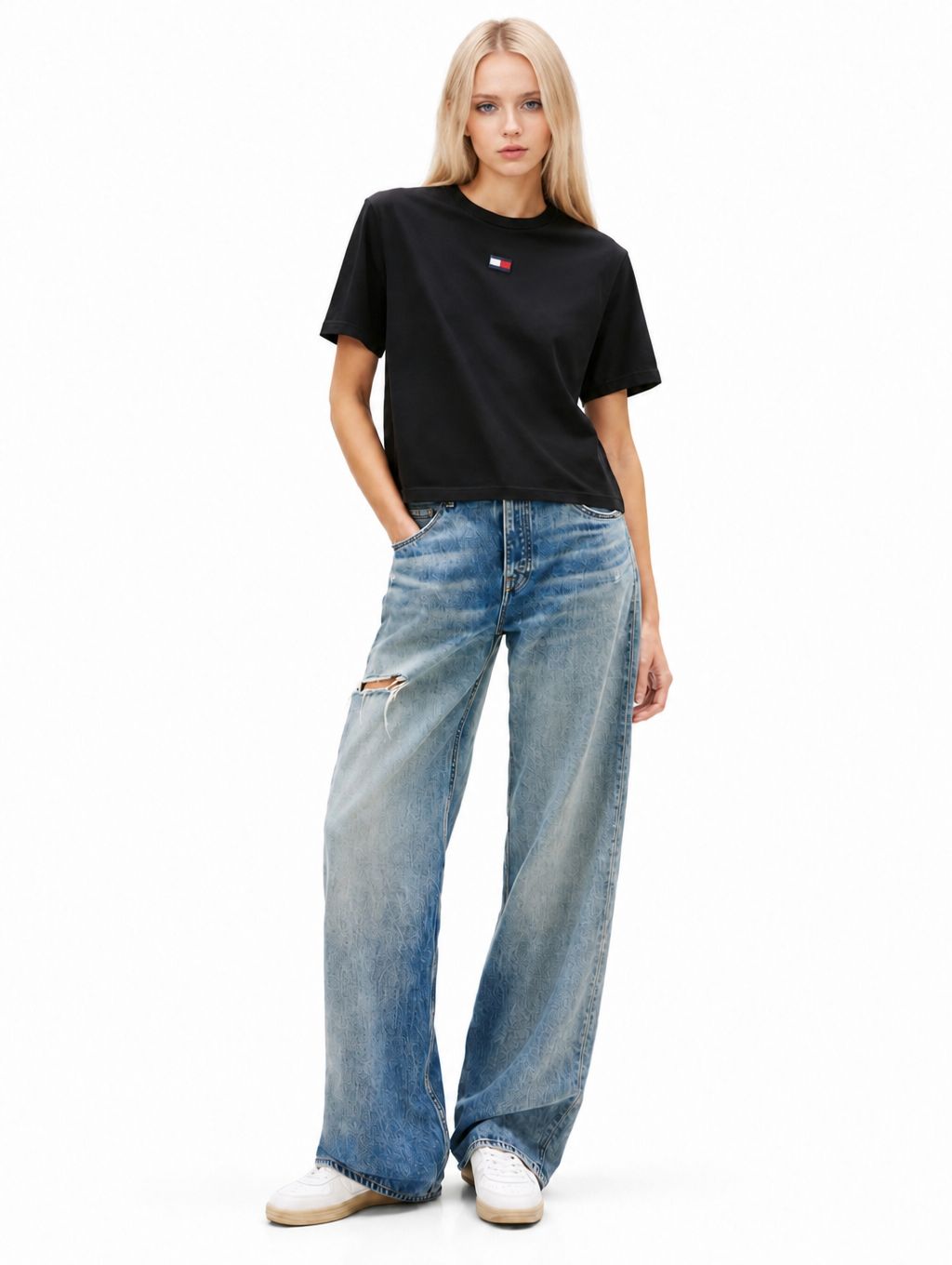 Full-length model photo with a black logo T-shirt, blue wide-leg jeans and white sneakers on a white background