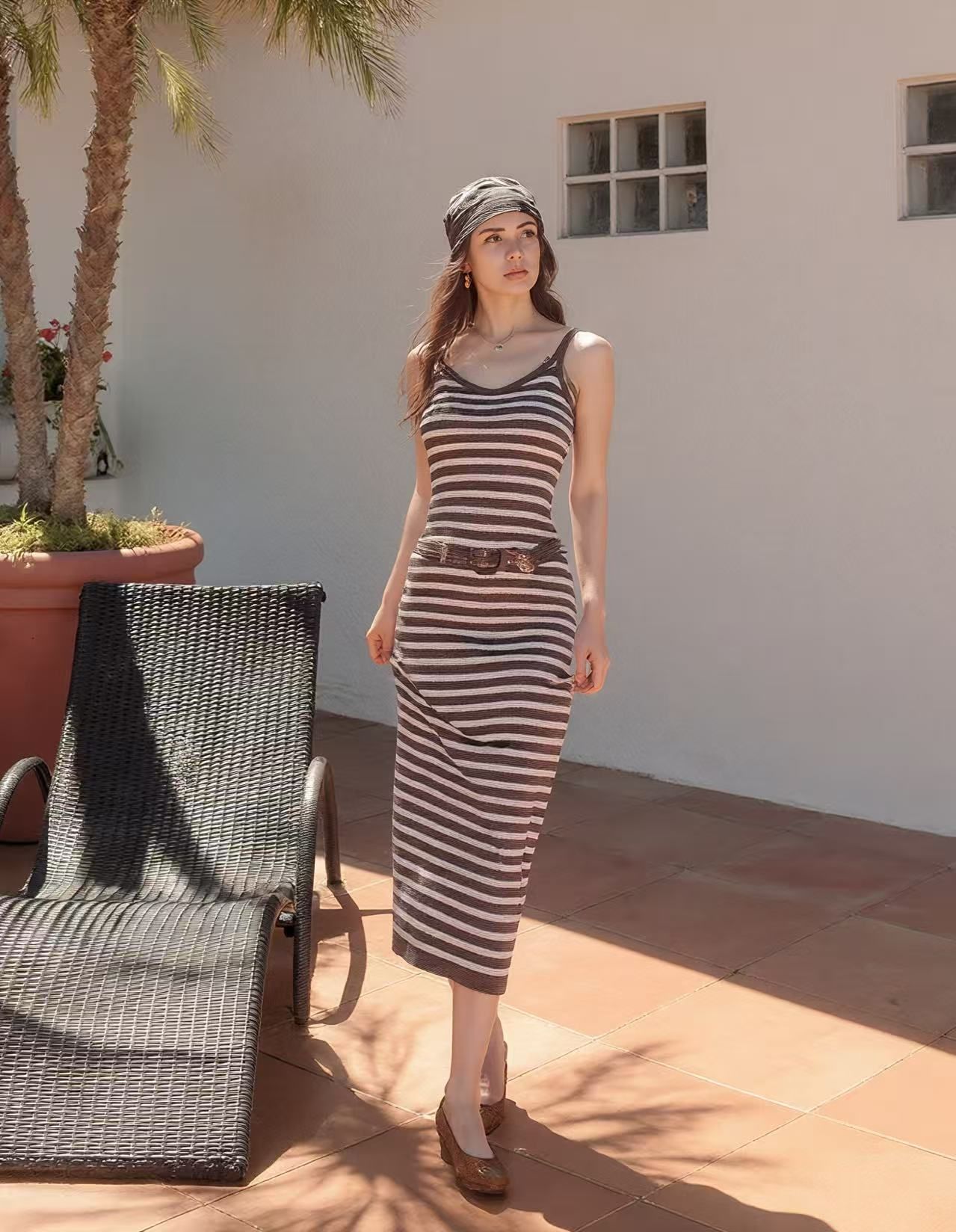 Model on a sunny patio wearing a fitted brown-and-cream striped dress, a brown belt and a matching head scarf