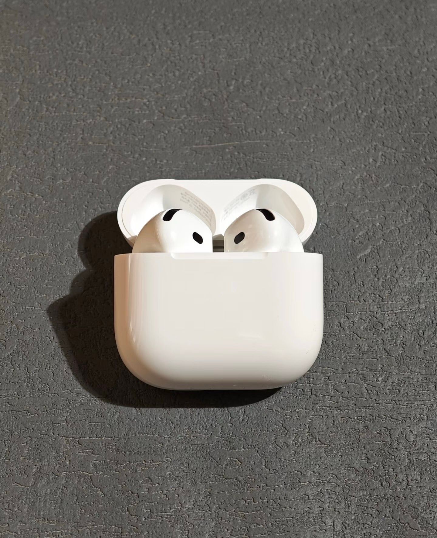 Wireless earbuds in an open charging case on a gray surface