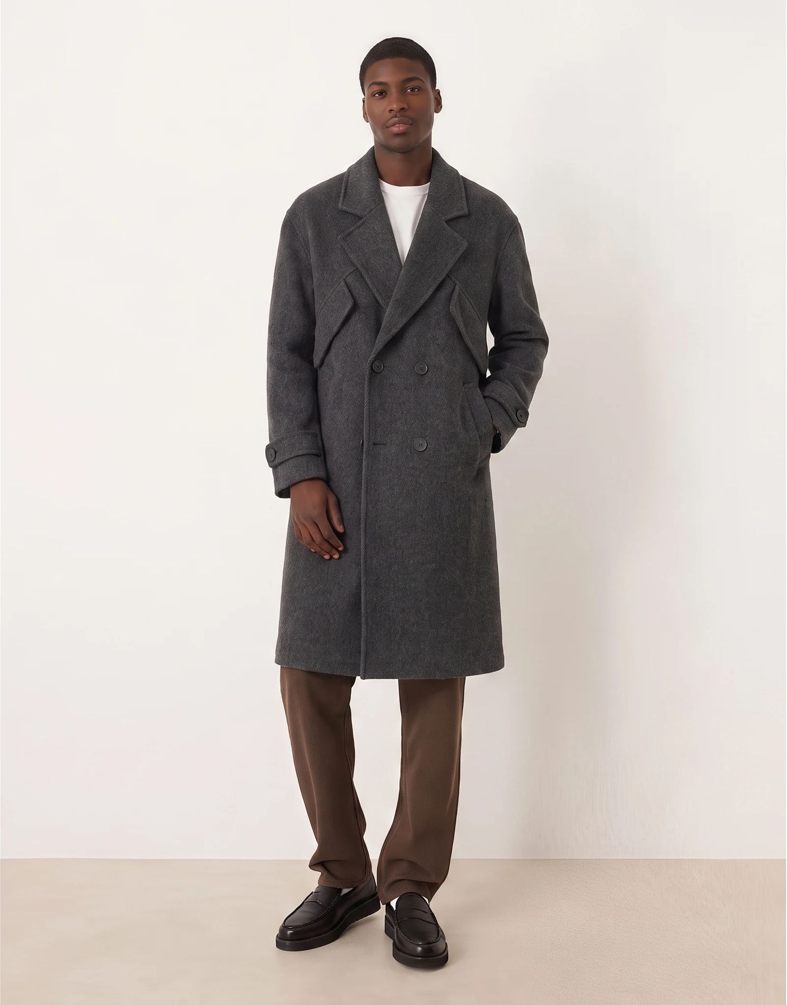 A model wearing a gray coat with one hand in a pocket.