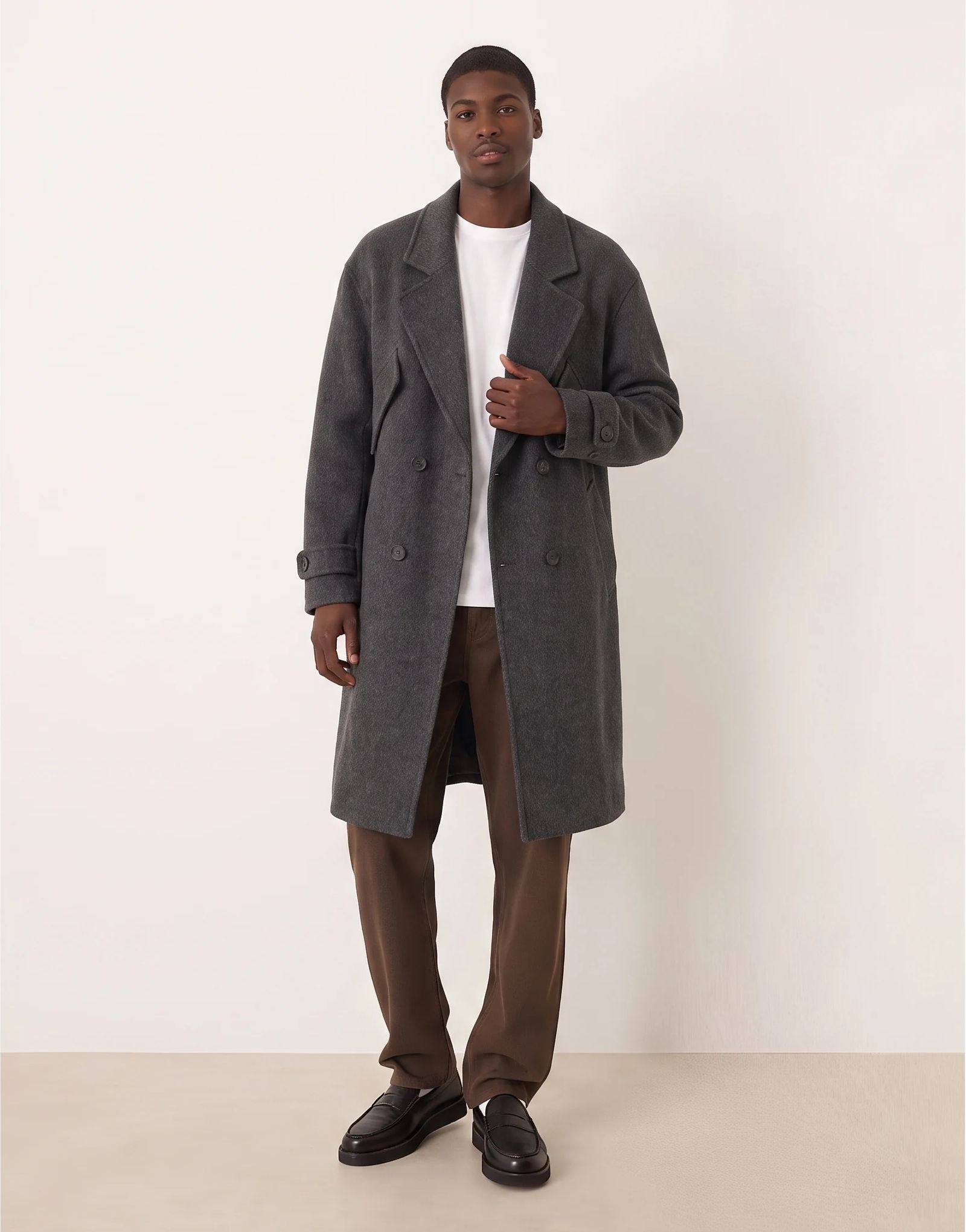 A gray coat worn open to reveal the shirt beneath it.