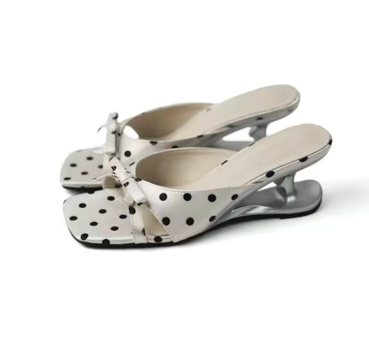 White polka-dot mule with a square open toe, a bow at the strap and a sculpted chrome heel