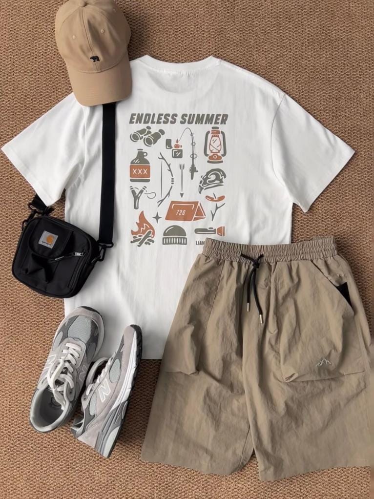 Original men's flat-lay outfit with a printed white T-shirt, khaki shorts, beige cap, black crossbody bag and gray sneakers