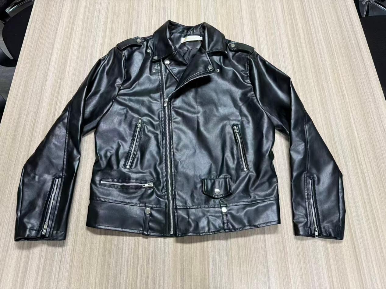 Original black biker jacket laid flat with asymmetric zipper, shoulder epaulettes, zipped pockets, flap pocket and cuff zippers