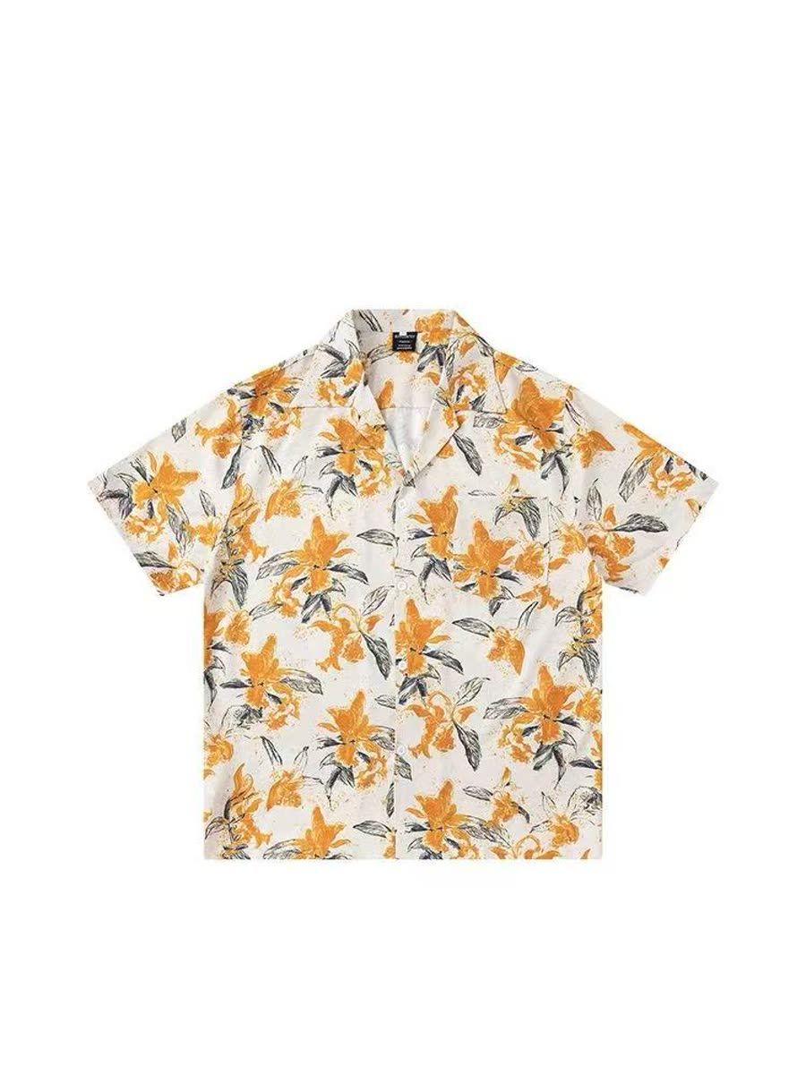 A white short-sleeve camp-collar shirt photographed flat, printed with orange lilies and grey-green leaves