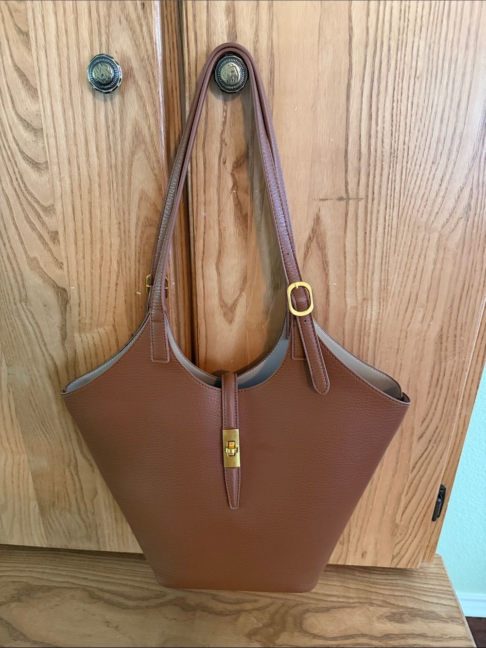 Brown handbag photographed against a wooden cabinet