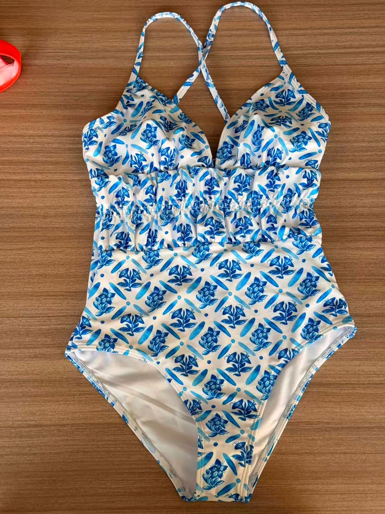 Blue and white floral swimsuit photographed flat on a wooden surface