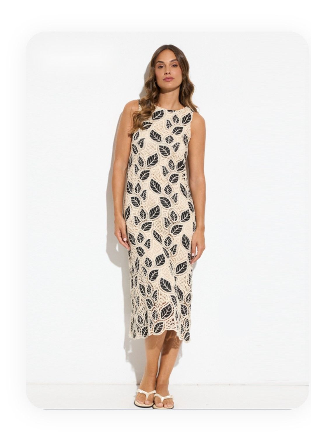 Vintage leaf-print sleeveless midi dress photographed on a young woman against a white wall