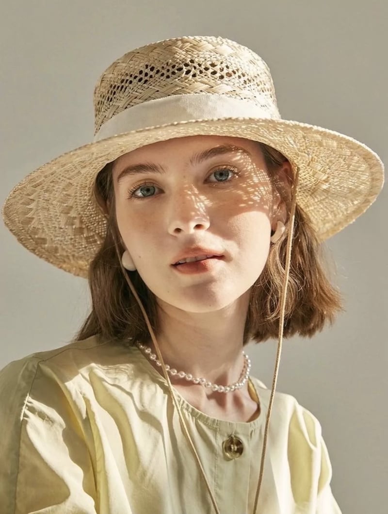 original test portrait of a woman in a woven straw hat casting dappled sunlight across her face