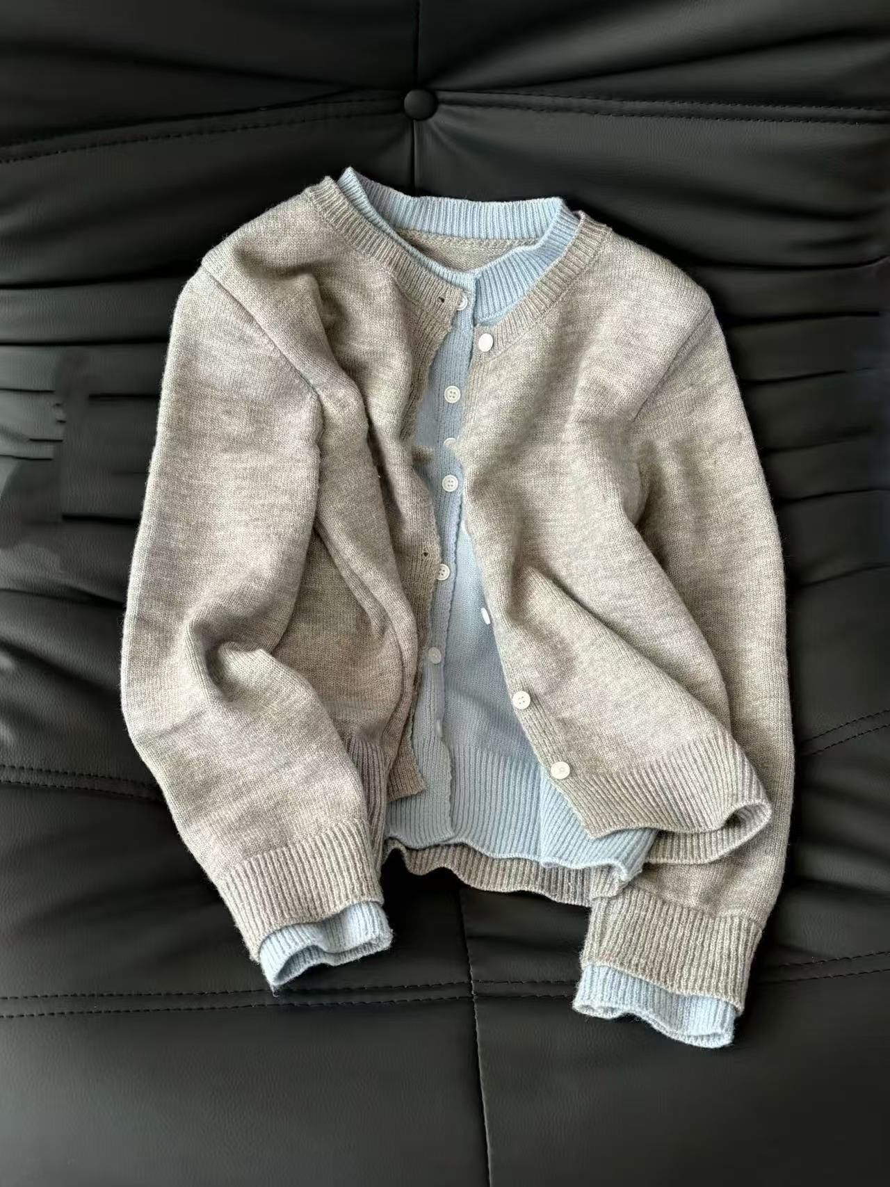 Two layered garments on a dark sofa with unclear edges