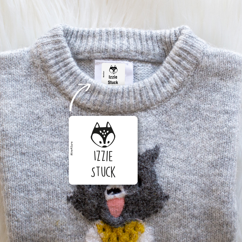 A knit sweater with a woven name label reading Izzie Stuck — the kind of small printed garment text AI generators most often turn into gibberish