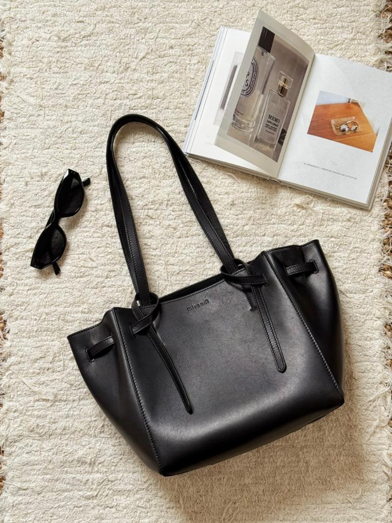 Source photo of a black leather tote lying flat on a cream rug