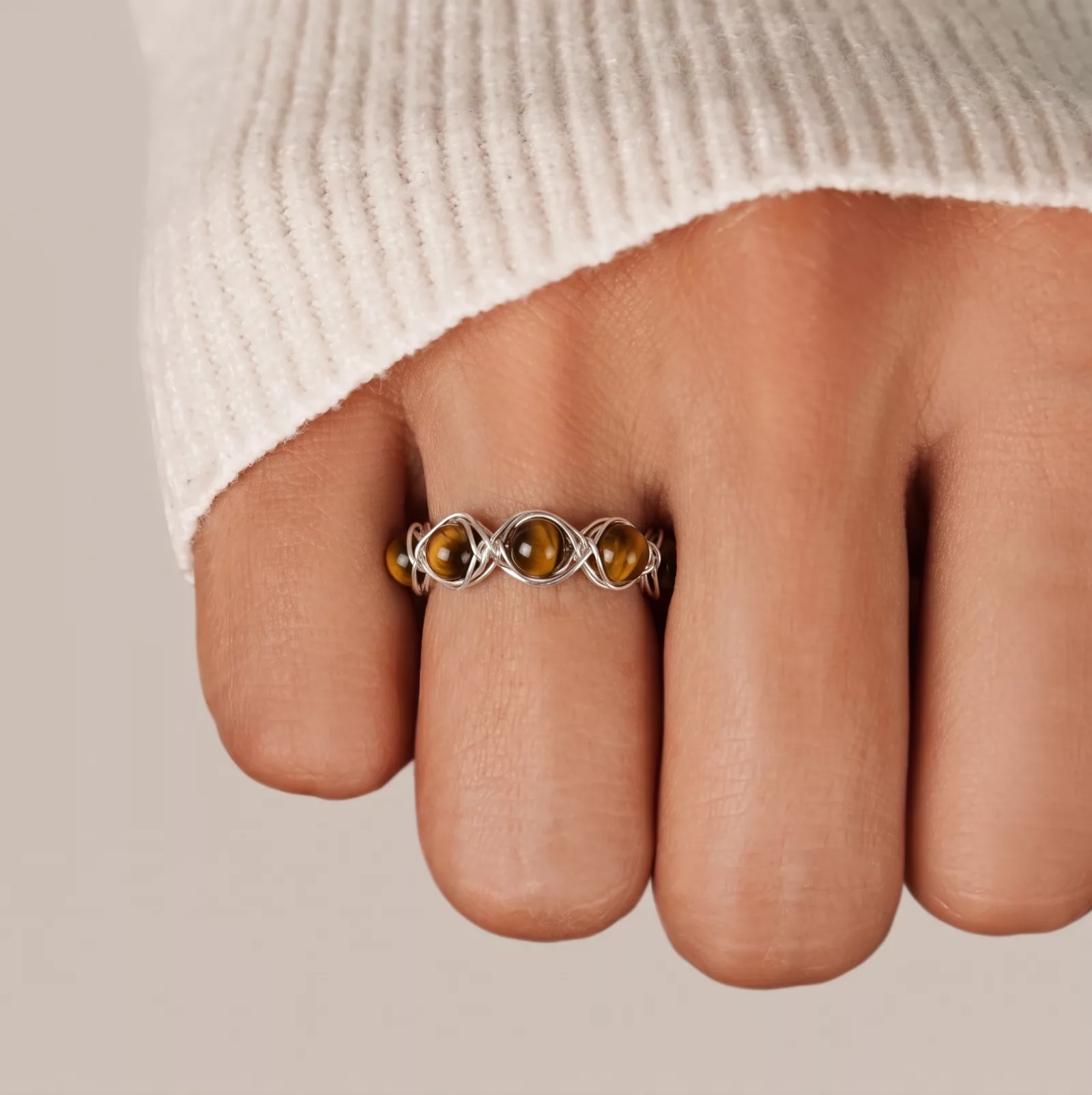Snappyit Jewelry Model output — tiger's eye wire-wrapped ring worn on a model's finger at correct scale with natural skin tone and lighting