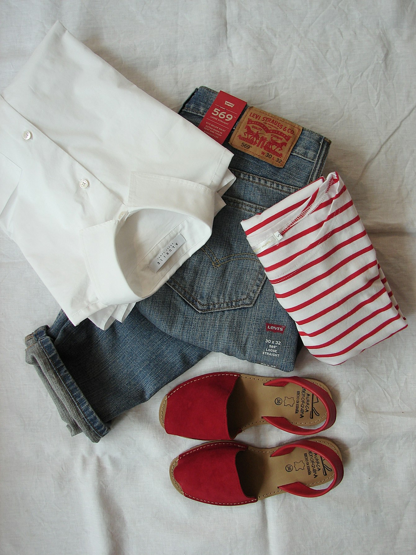 A styled flat lay clothing photoshoot — women's apparel arranged overhead on a neutral surface