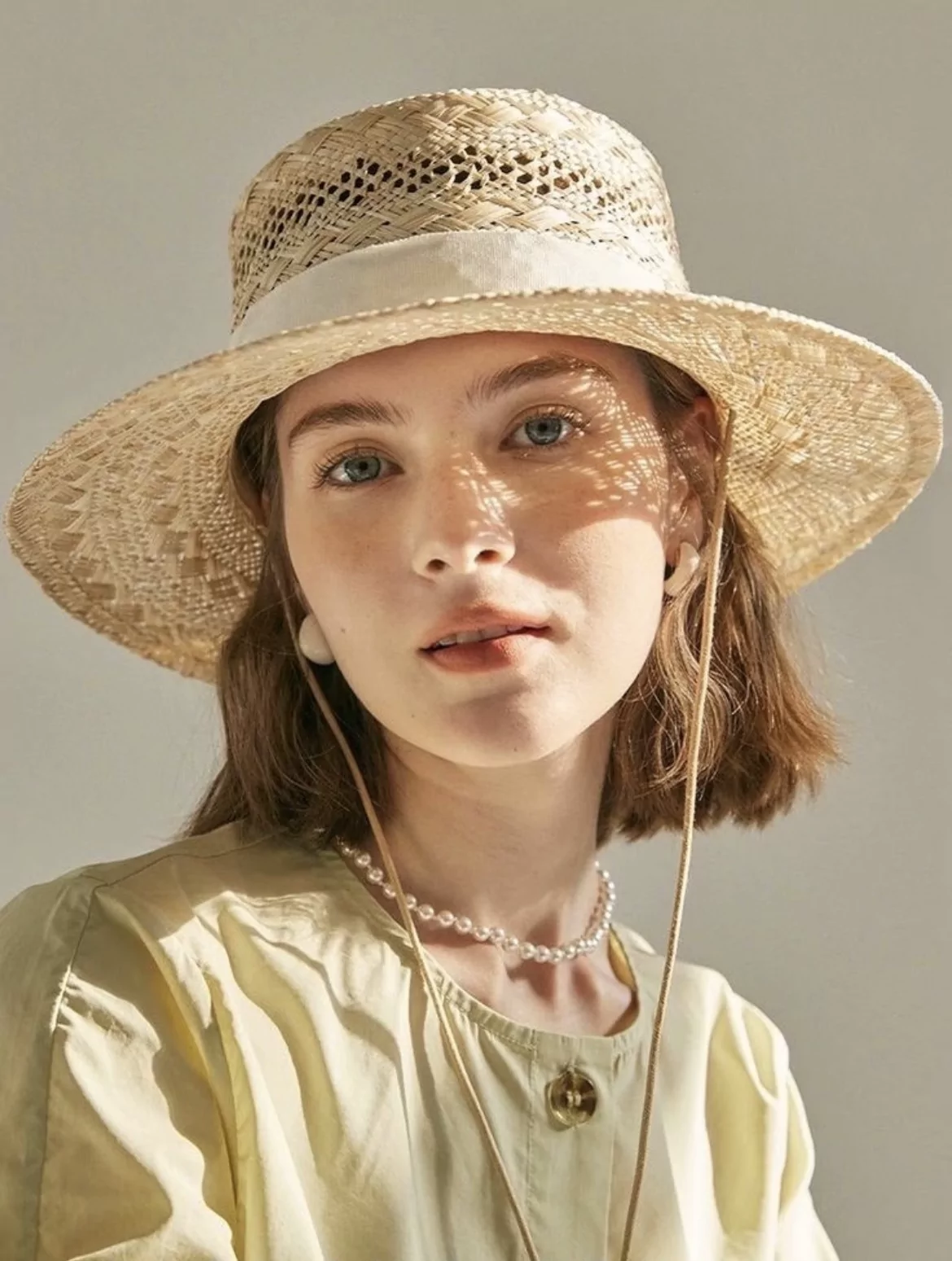 original test portrait of a woman in a woven straw hat casting dappled sunlight across her face