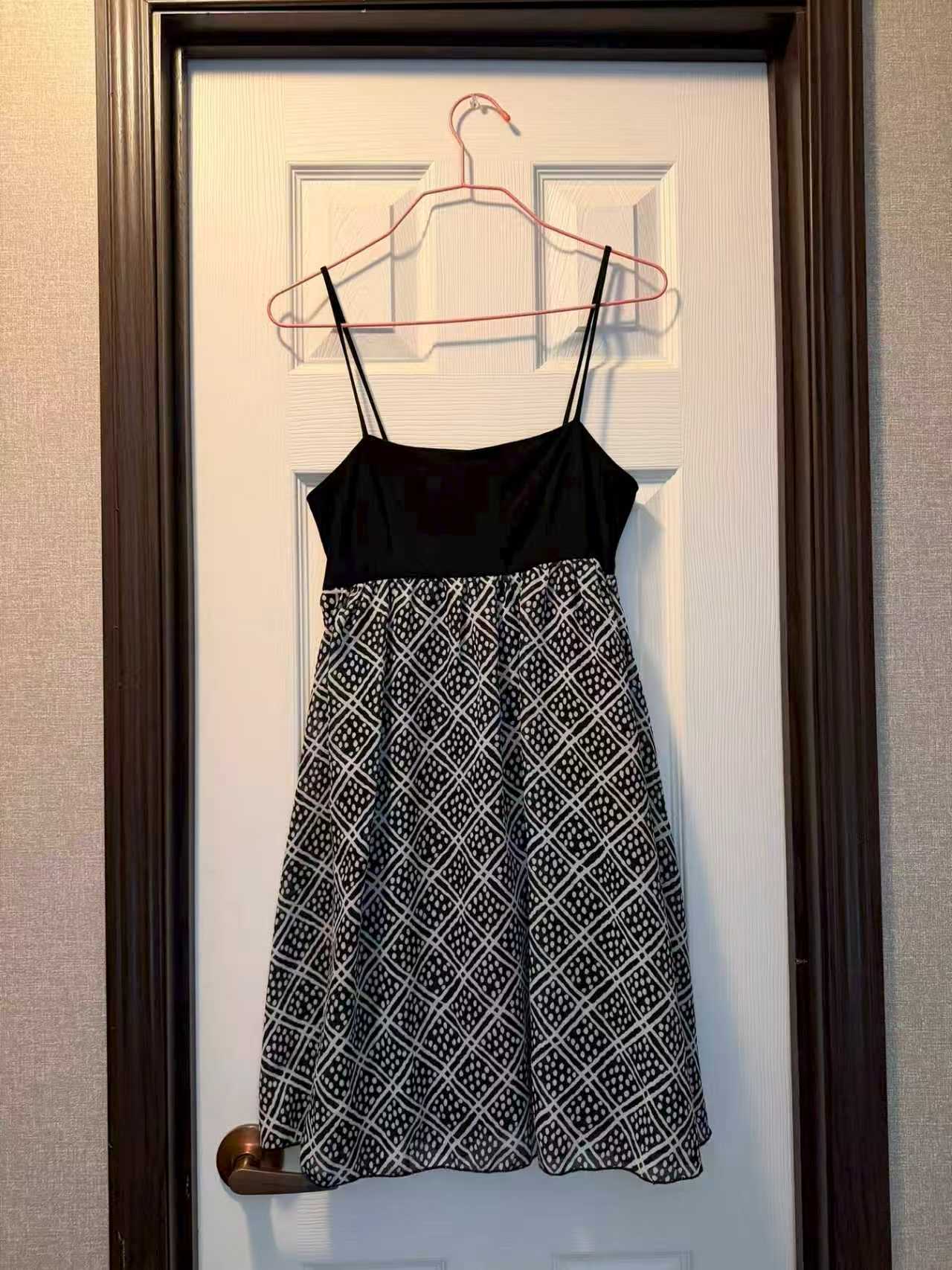 Full-length hanger photo of a black and white patterned dress with visible straps and hem