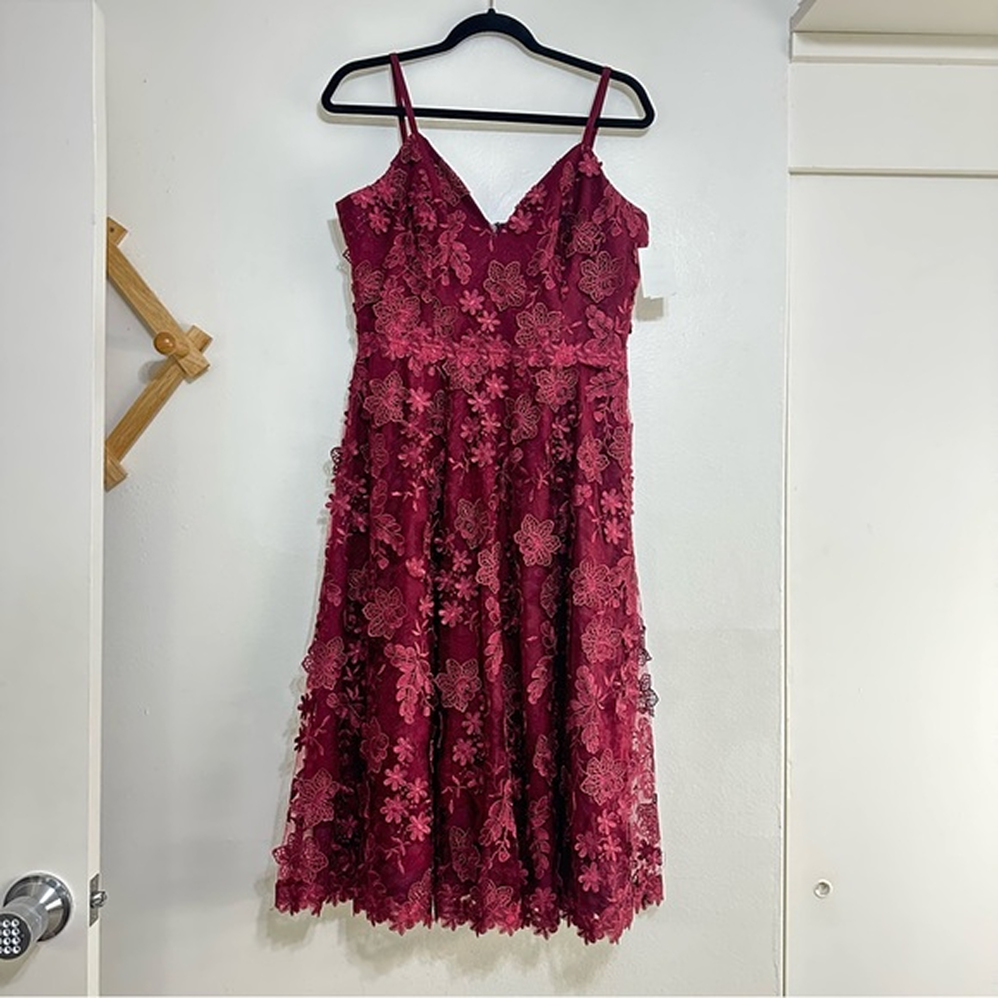 Burgundy lace dress hanging on a hanger — casual phone photo before AI processing