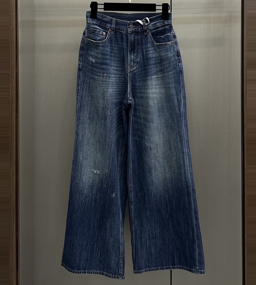 Dark wash wide-leg jeans hanging in front of a frosted glass cabinet door, phone photo