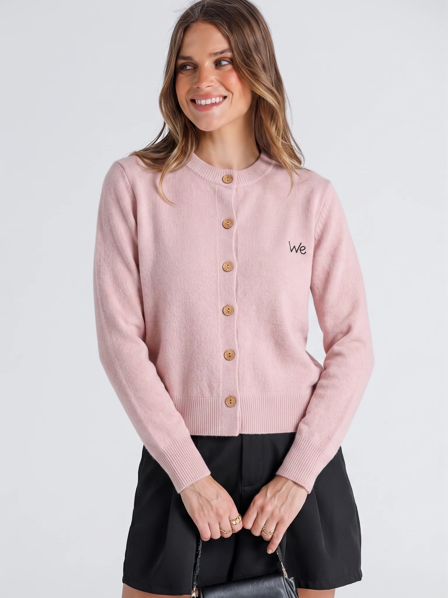 Front view of a model wearing a pink cardigan, with its buttons and hem visible.