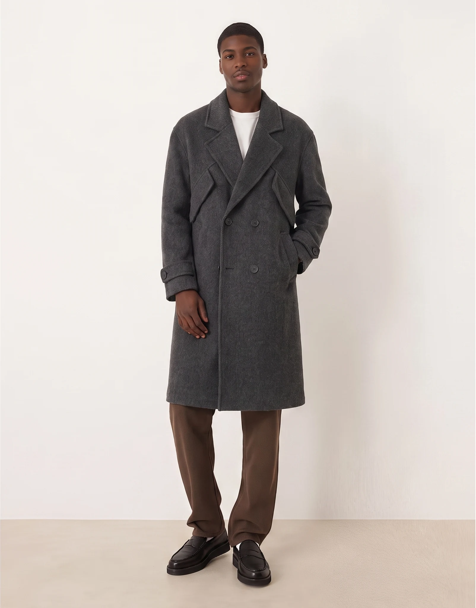 A model wearing a gray coat with one hand in a pocket.