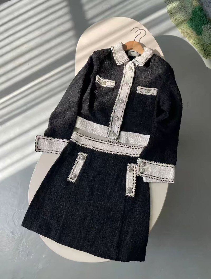 Test input 1: a black tweed jacket and skirt set photographed on a hanger with a phone