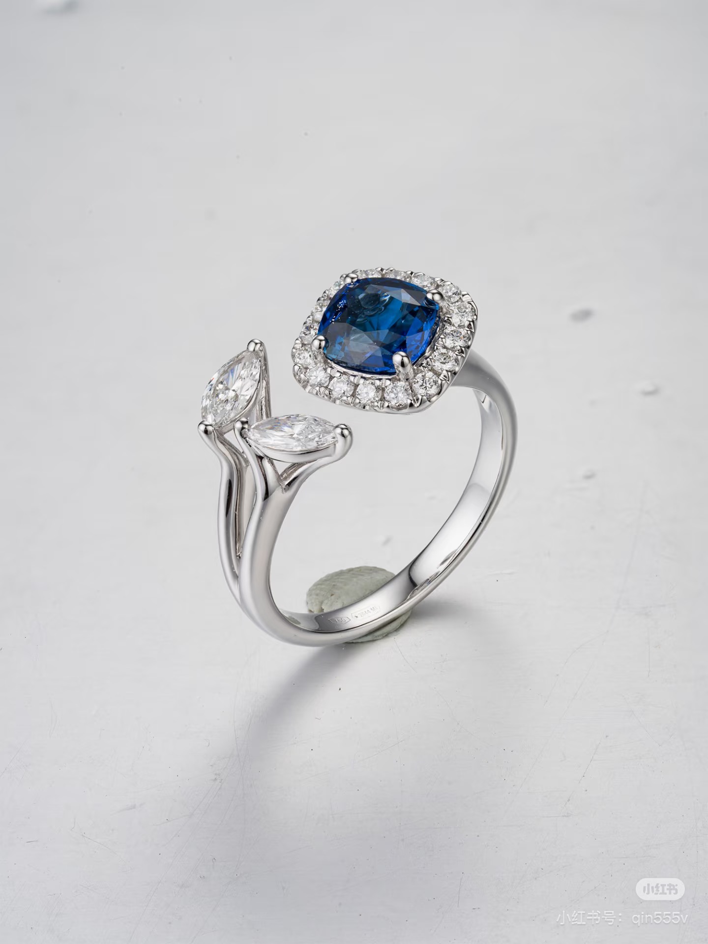 Raw photo: sapphire and diamond open-style ring on a scratched light-grey surface