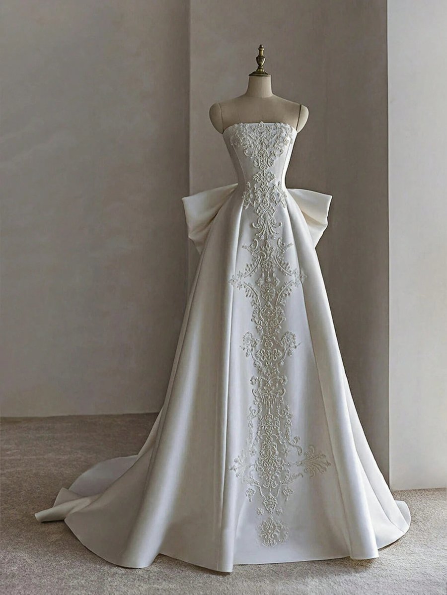 A white satin gown photographed on a visible dress form / mannequin in a studio