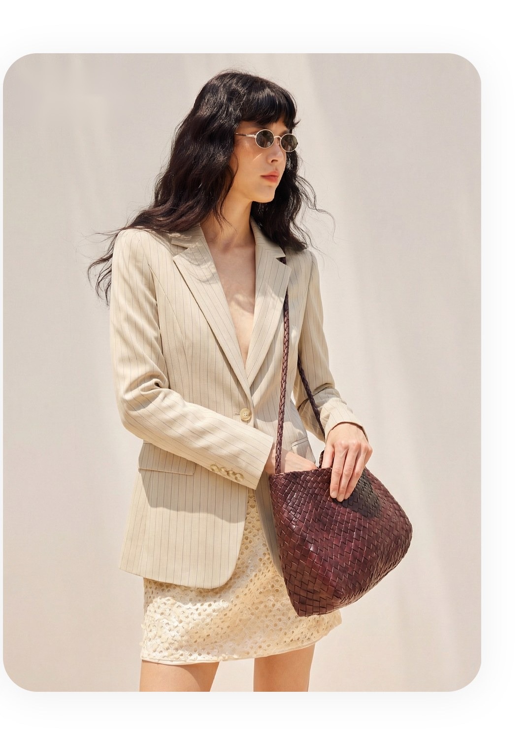 Derselbe Nadelstreifenblazer im Stil eines weiblichen AI-Modells mit Vintage-Tasche in bürotauglicher Umgebung